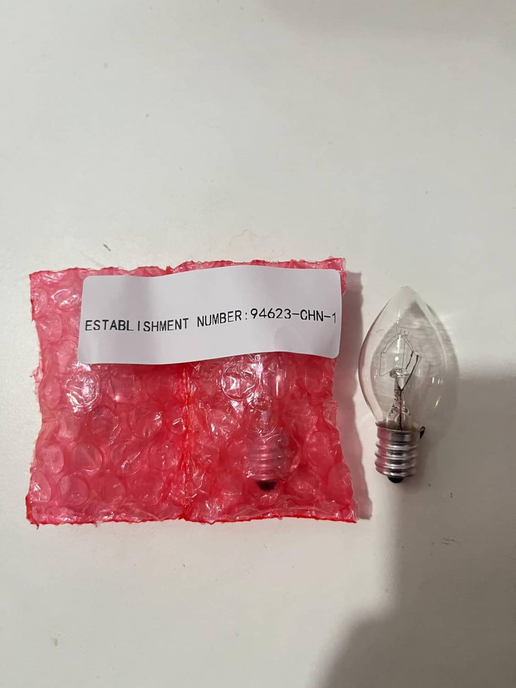 E12 replacement bulb with clear glass and metal screw base; spare bulbs in sealed bag