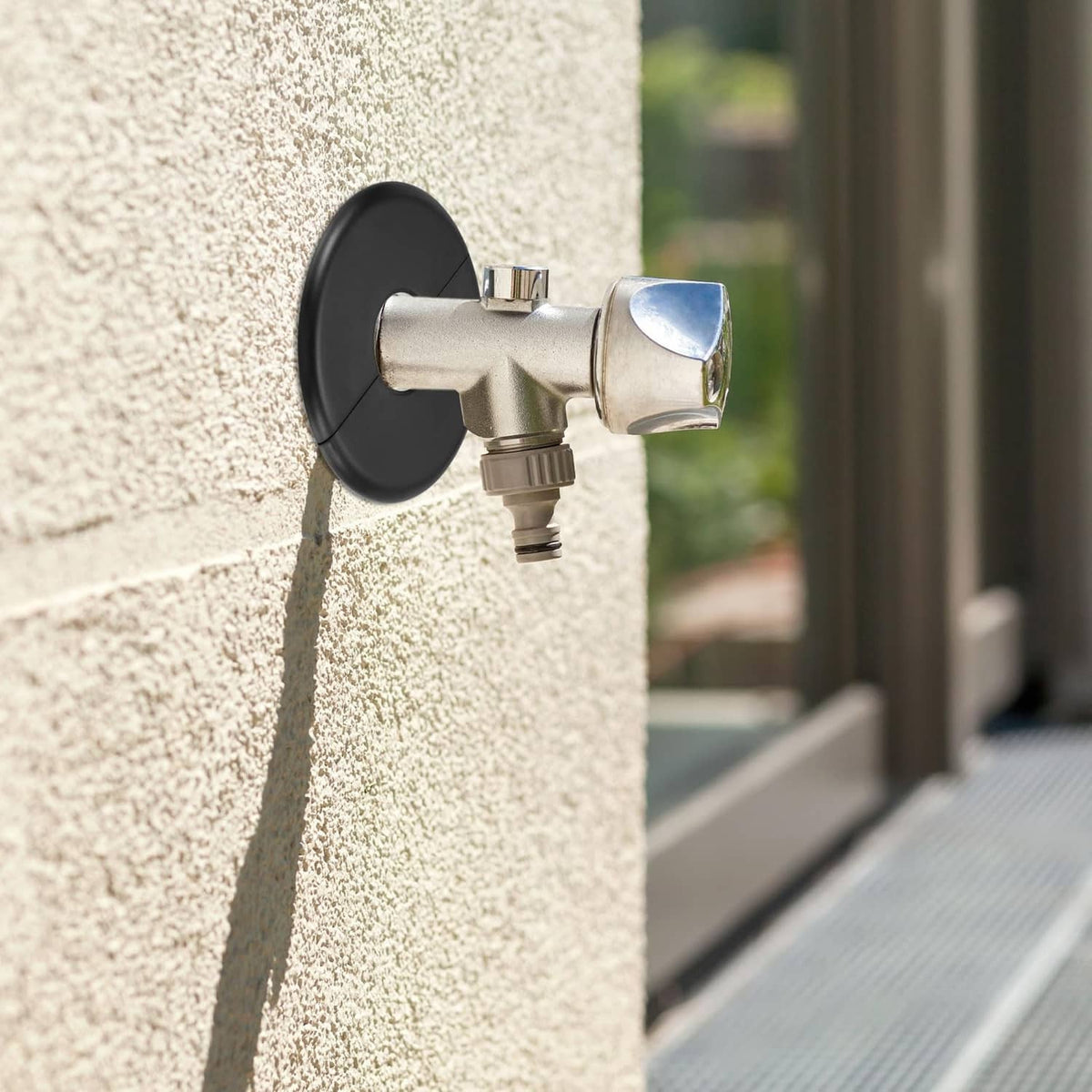 Black round flange cover around a pipe inlet on a textured wall