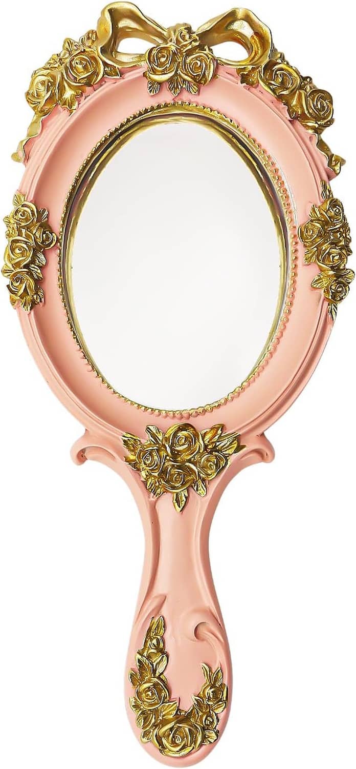 Pink handheld mirror with rose-gold embossed roses on oval frame and curved handle