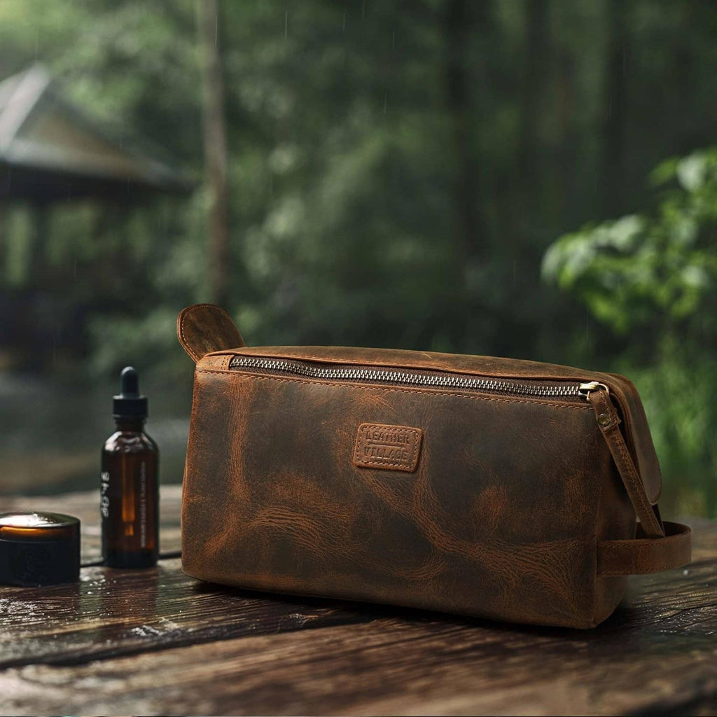 Brown leather toiletry bag on wooden surface with front zip and crossbody strap