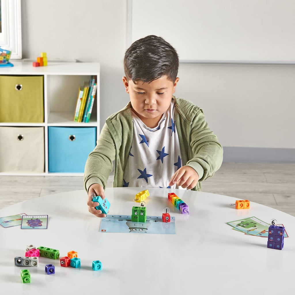 Child building with colorful Numberblocks cubes at a table with activity cards