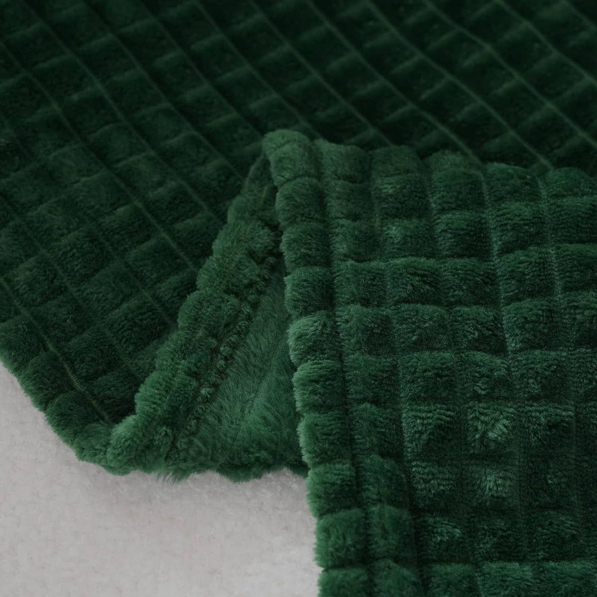 Dark green flannel fleece throw blanket close-up, quilted-looking waffle fabric pattern