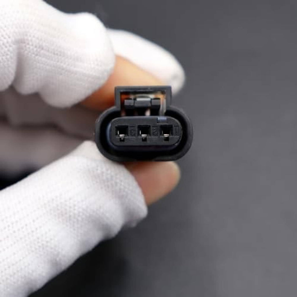 Camshaft position sensor connector plug with 3-pin contacts held in a gloved hand