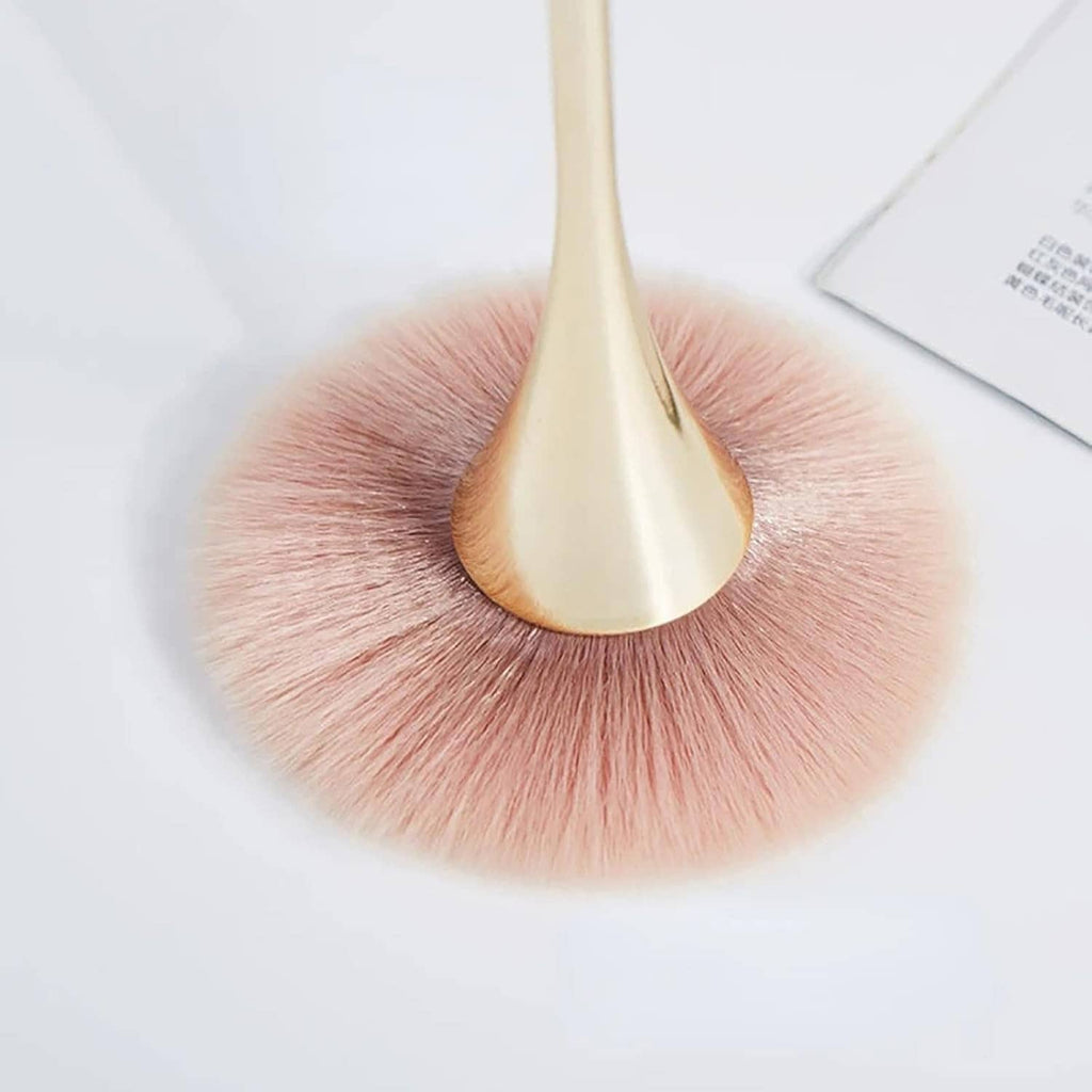 Close-up of gold-handled nail dust removal brush with soft pink bristles