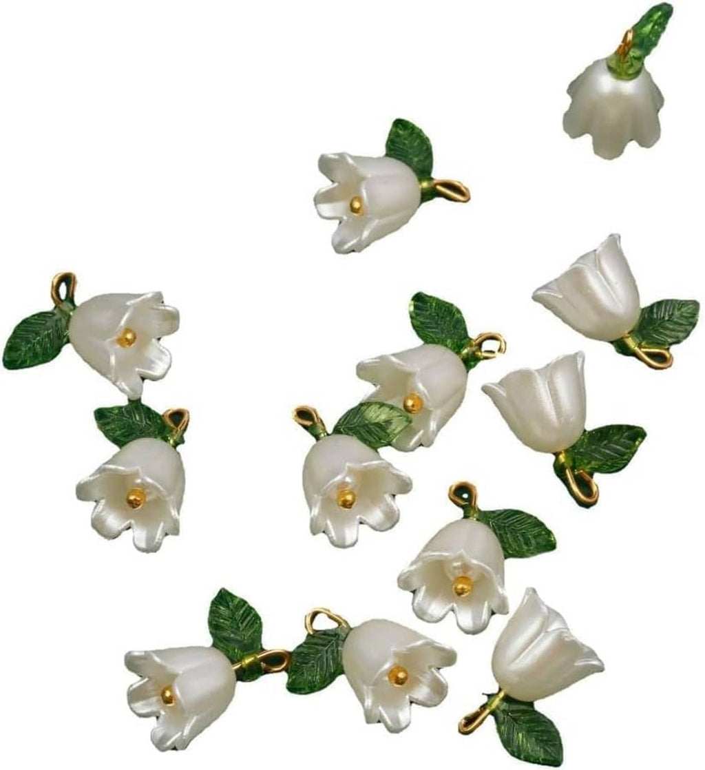 White bell orchid pendant beads with green leaves and gold loop rings, scattered view