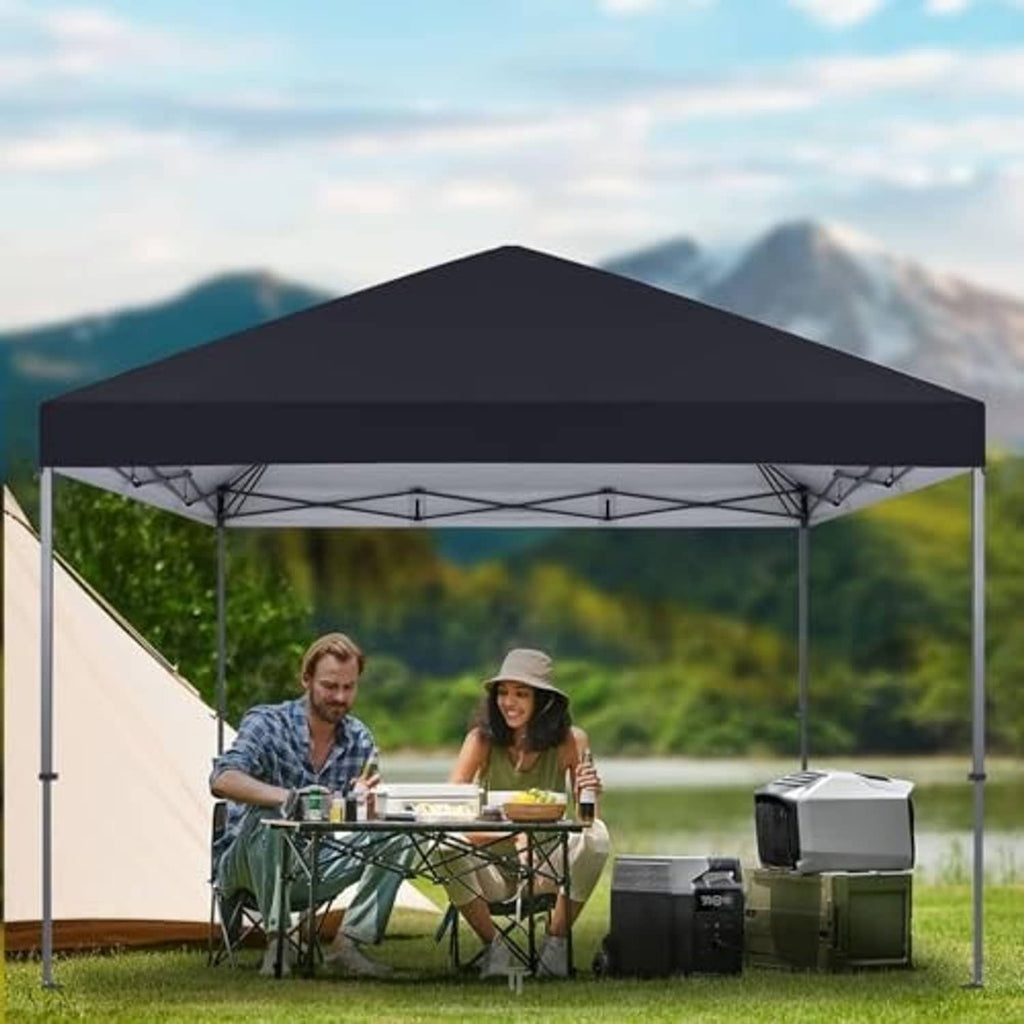 Black pop-up canopy top outdoors over metal legs, covering a picnic table