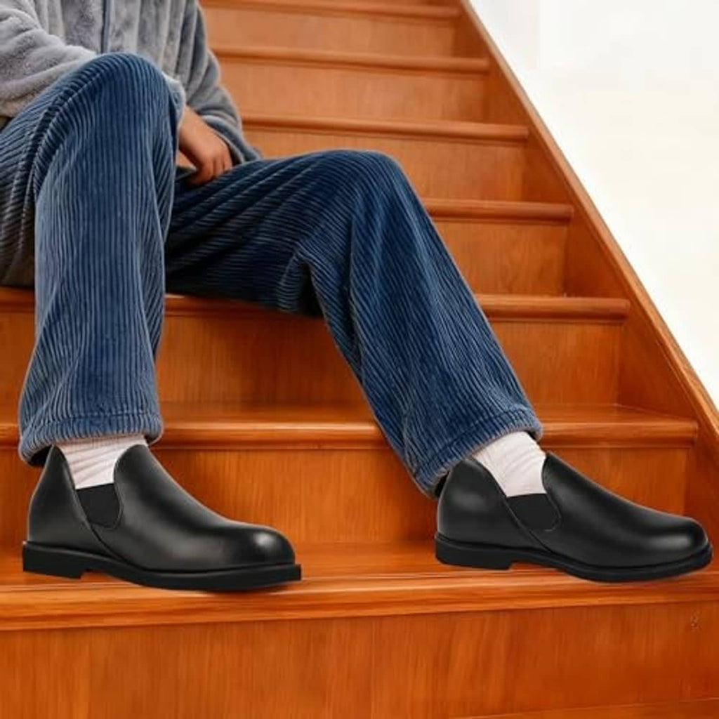 Men's black leather slip-on slippers worn on wooden stairs with blue corduroy pants