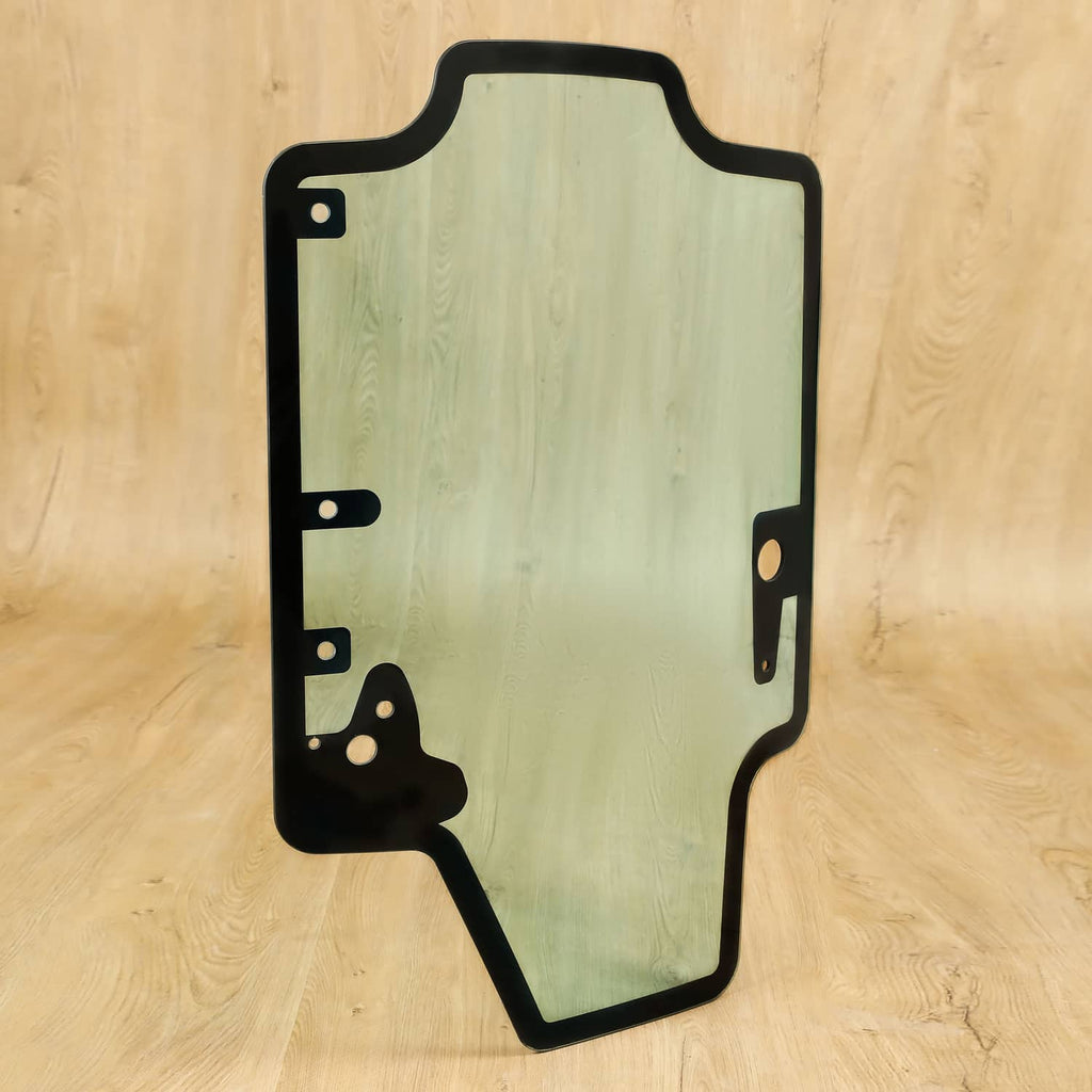 Skid steer door glass panel with black frame and side mounting brackets, tinted light green
