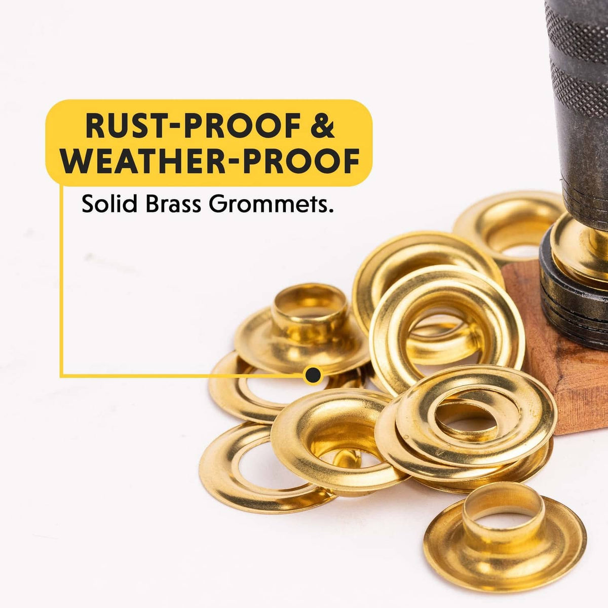 Pile of solid brass grommets with a black punch tool and anvil piece