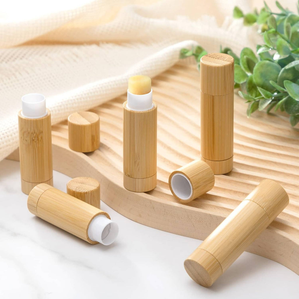 Bamboo empty lipstick tubes with white inner caps, arranged on a wooden tray