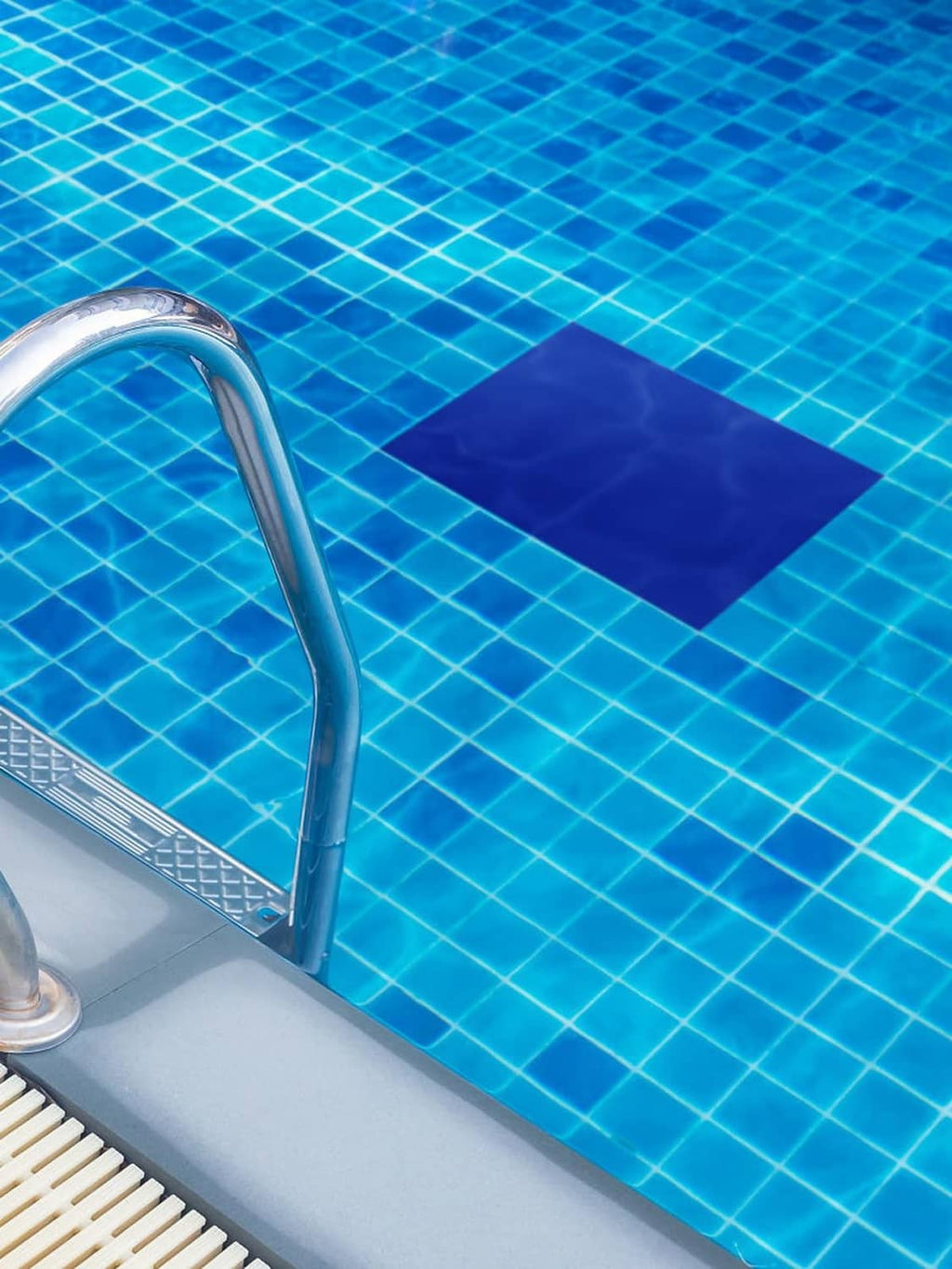 Dark blue pool liner repair patch adhered to pool wall beside metal ladder