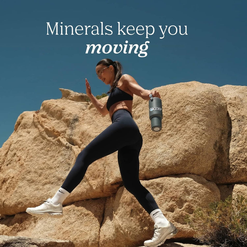 Electrolyte supplement bottle held by a runner on rocky terrain