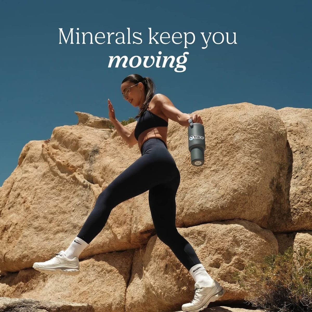 Electrolyte supplement bottle held by a runner on rocky terrain