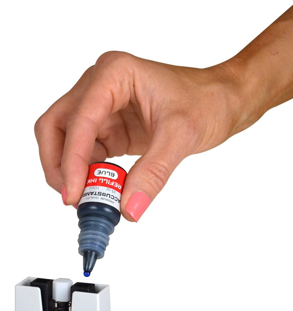 Hand holding red Accu-stamp ink refill bottle over ink cartridge slot