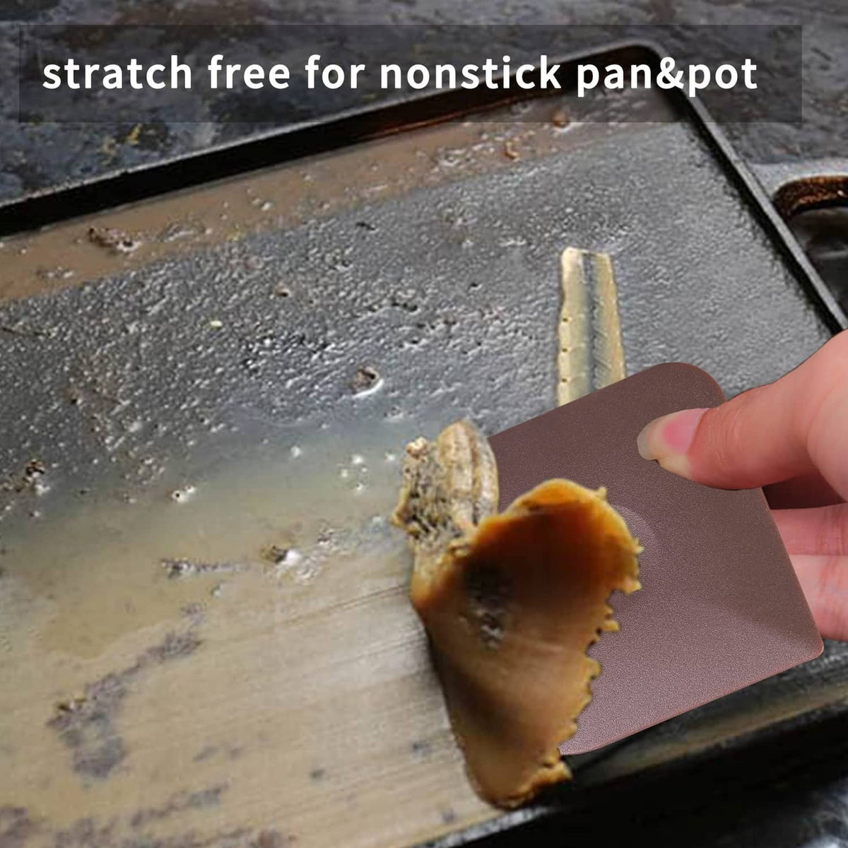 Hand holds a brown dish scraper pad removing stuck food from a pan