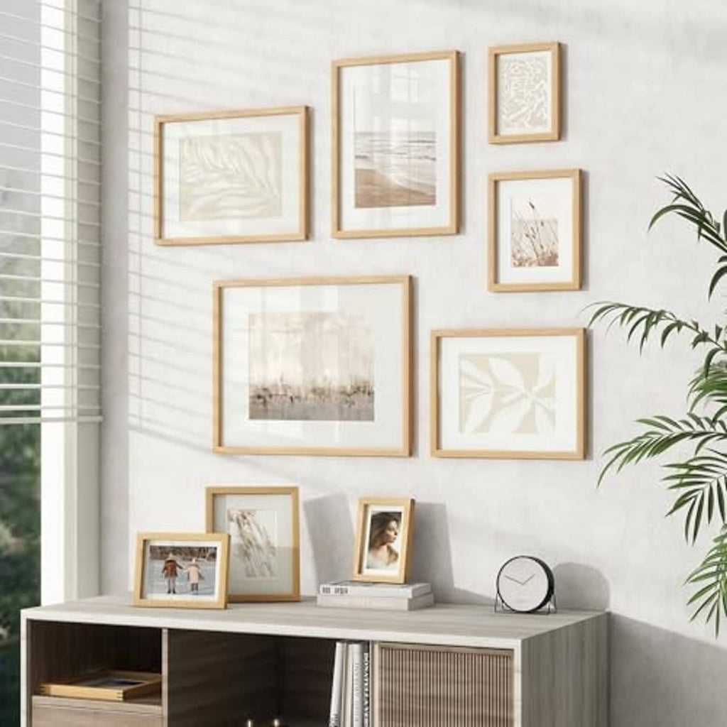 Natural oak photo frames arranged on wall above a console table