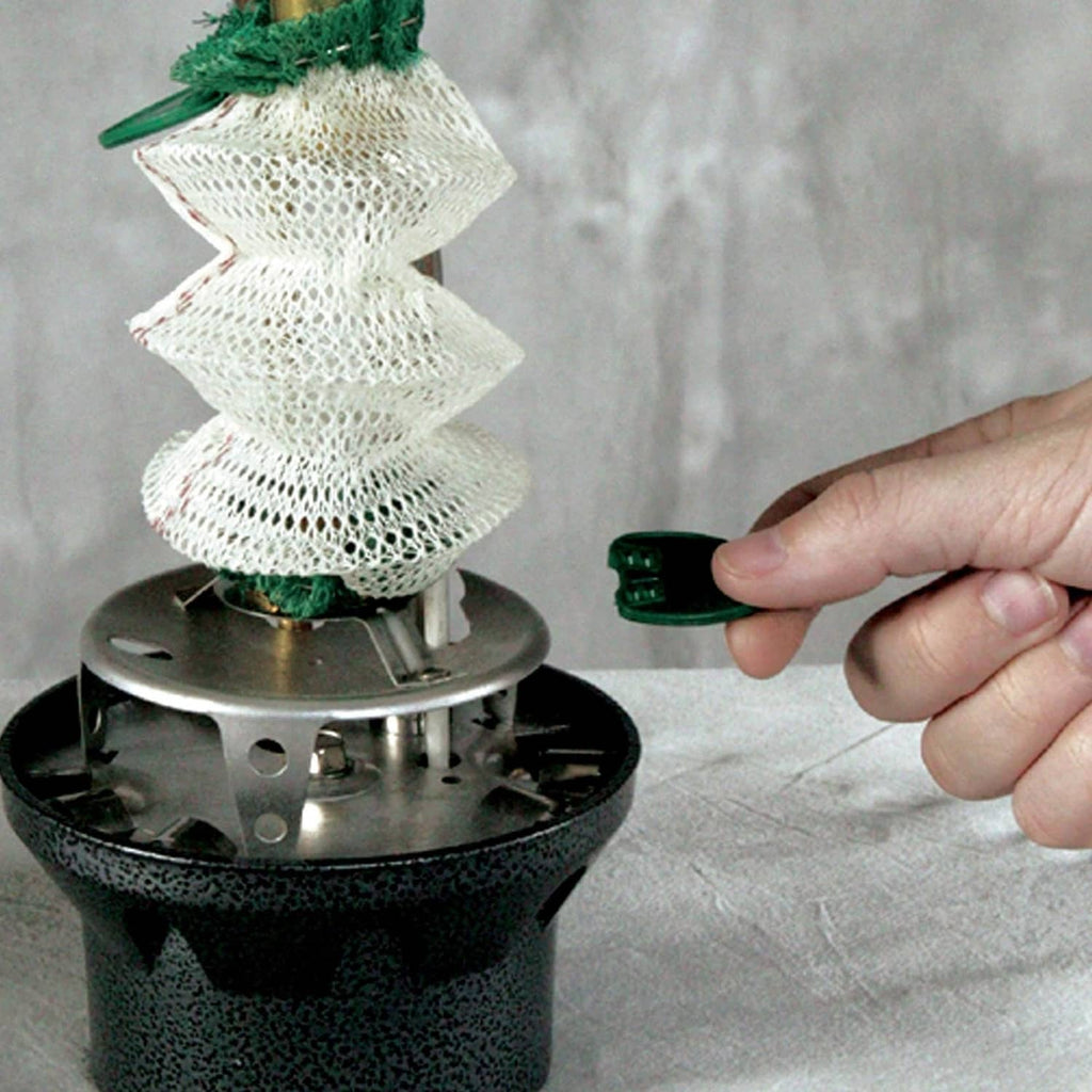 Green-and-white wick accessory seated on Coleman Northstar lantern burner with hand adjusting