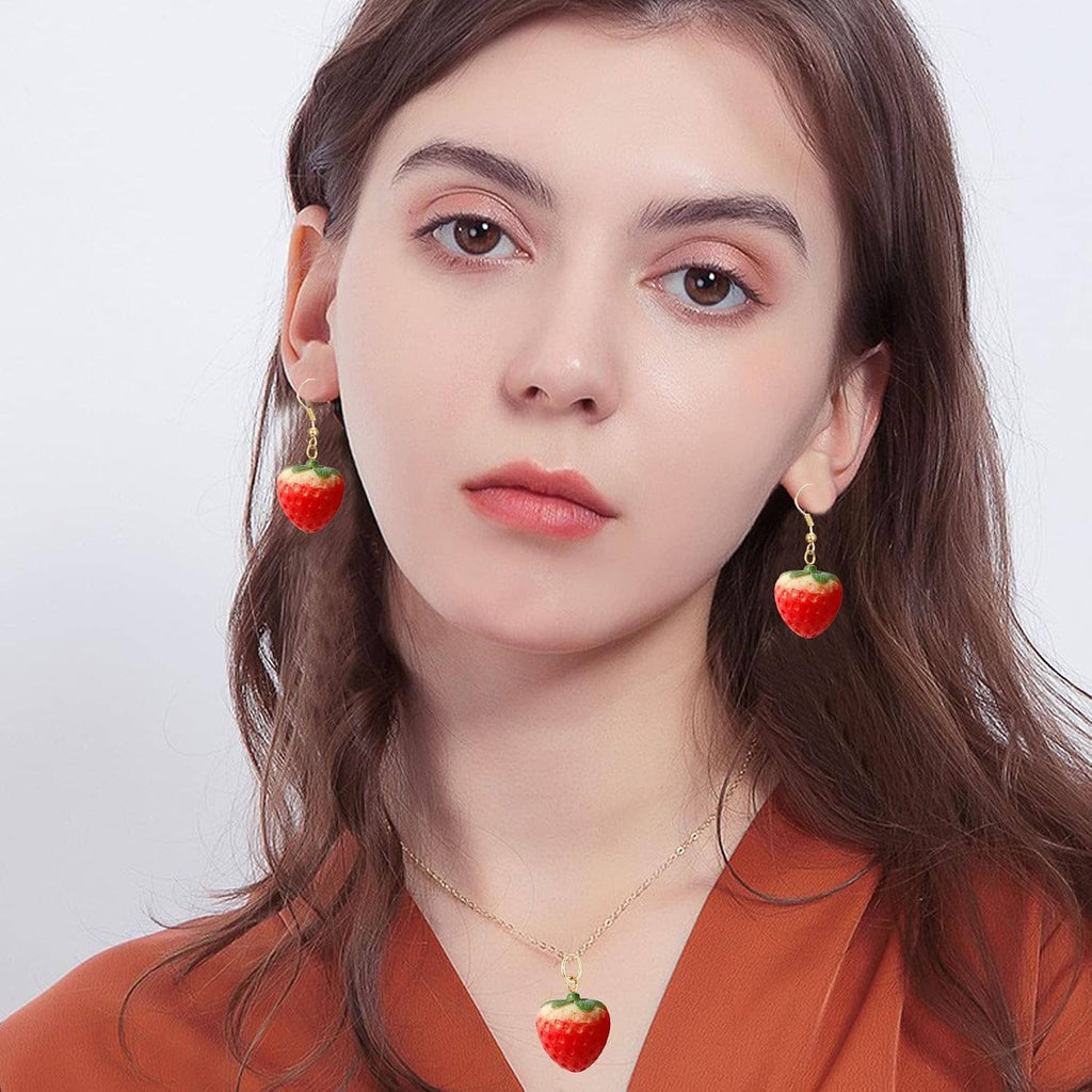 Woman wearing gold-tone strawberry pendant necklace and red dangle strawberry earrings