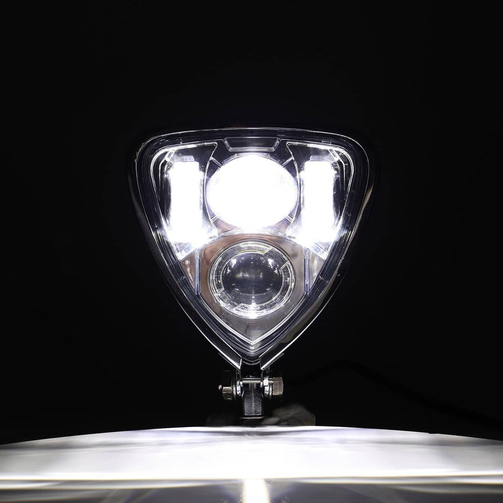 Triangular motorcycle headlight with lower round lamp glowing through clear lens