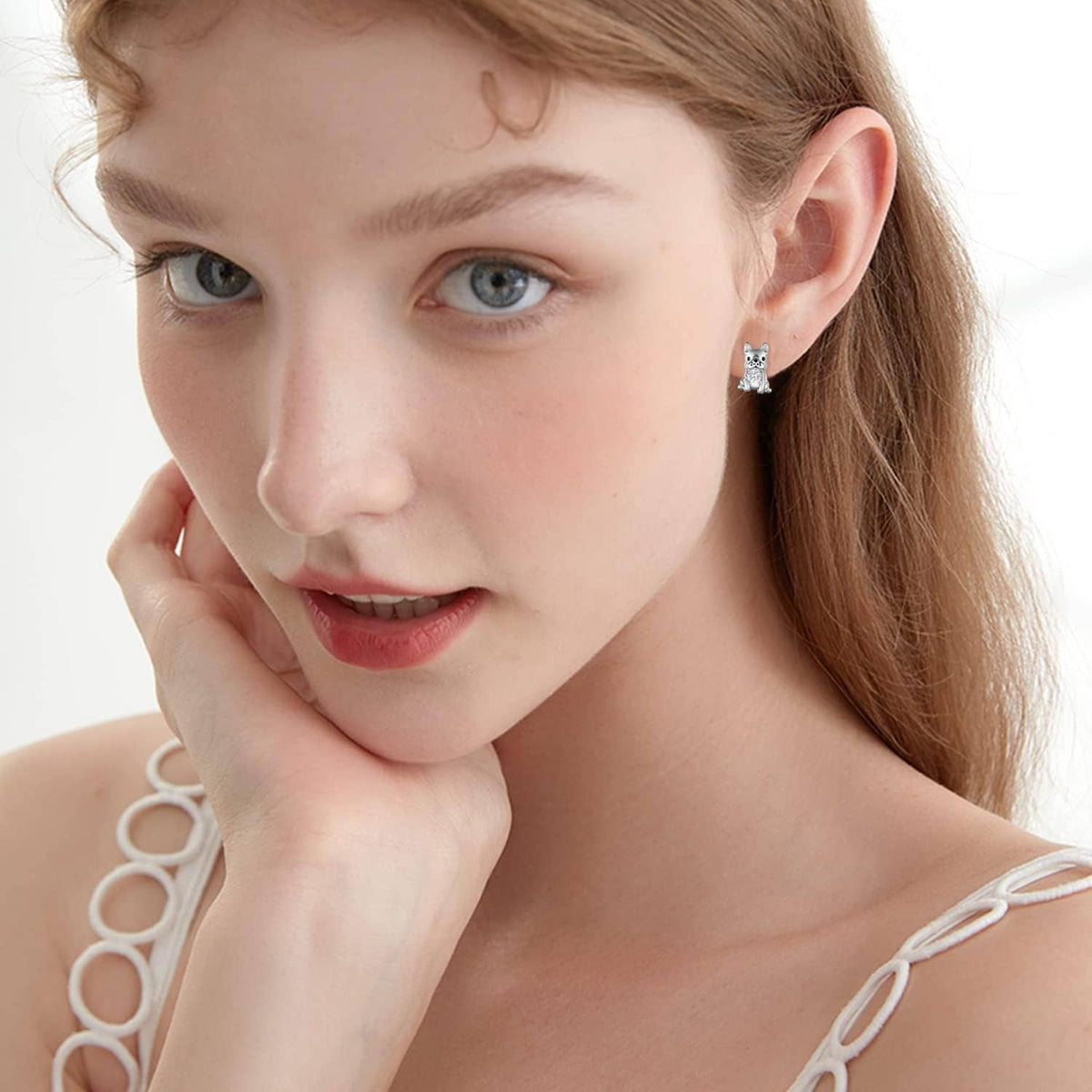 Woman wearing silver French bulldog stud earrings with clear crystal
