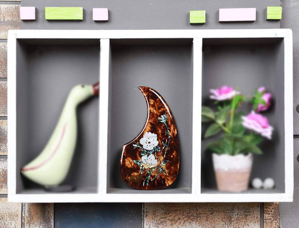 Tortoiseshell acoustic guitar pick guard with white flower abalone inlay shown in a display case