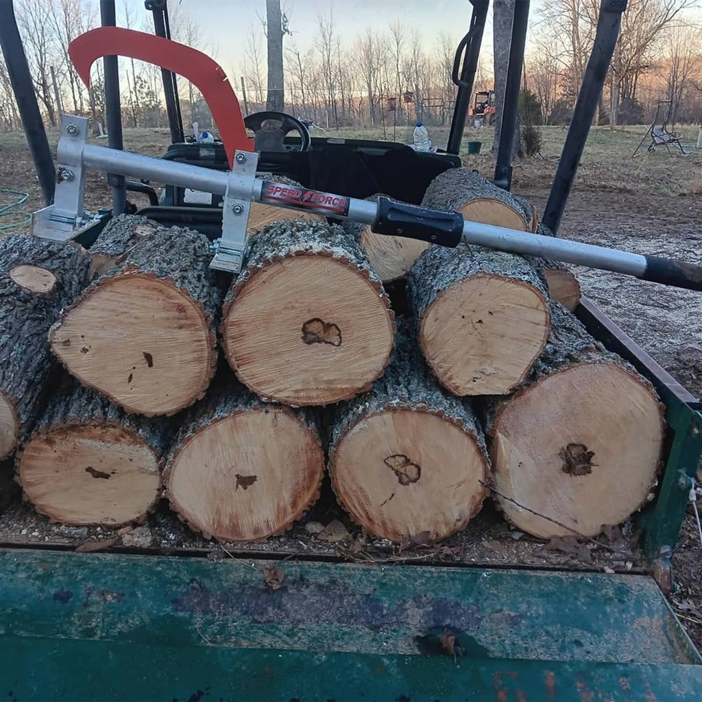 Wood jack mounted on a trailer with stacked logs, red hook and silver lifting beam
