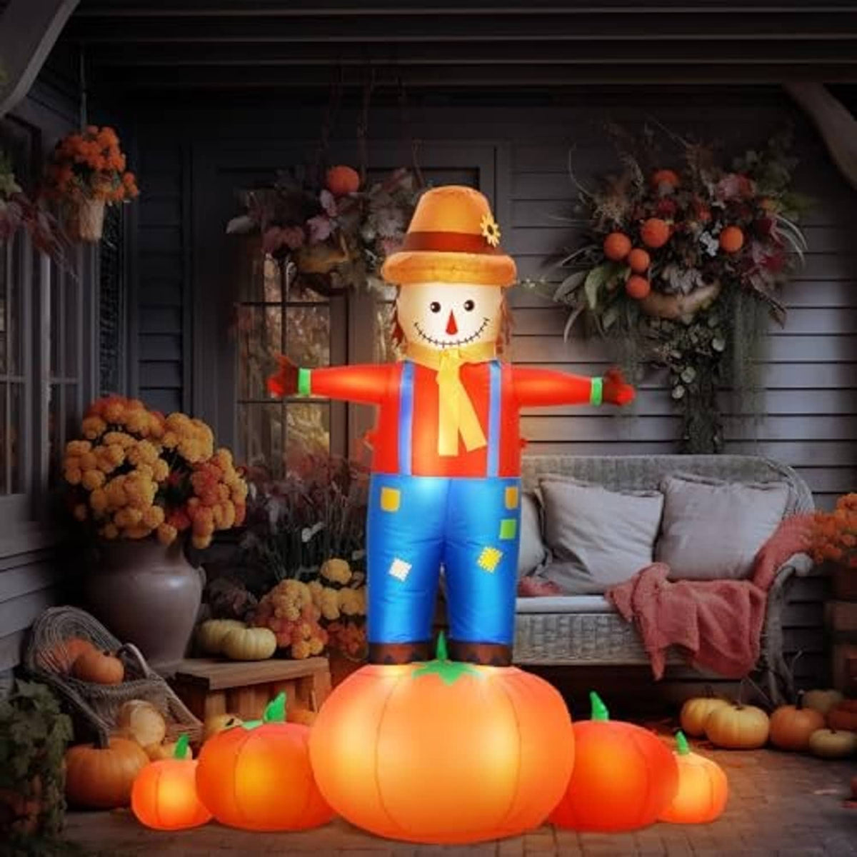 Inflatable scarecrow with pumpkin base on front porch, orange hat and blue overalls