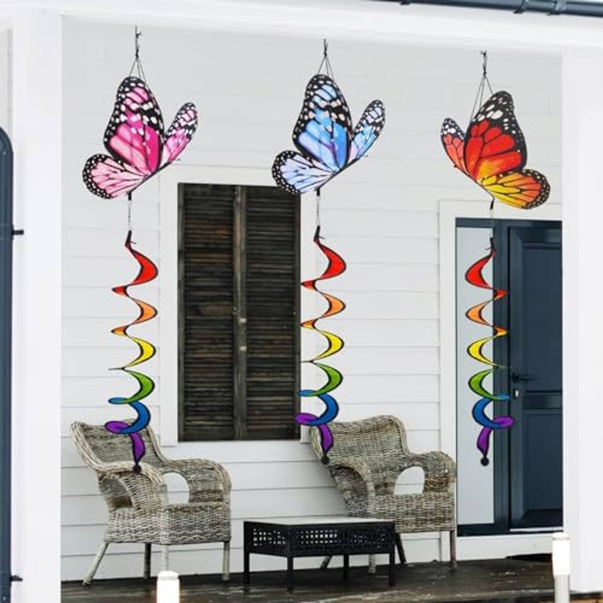Three butterfly wind spinners hanging outside with multicolor spiral ribbon tails