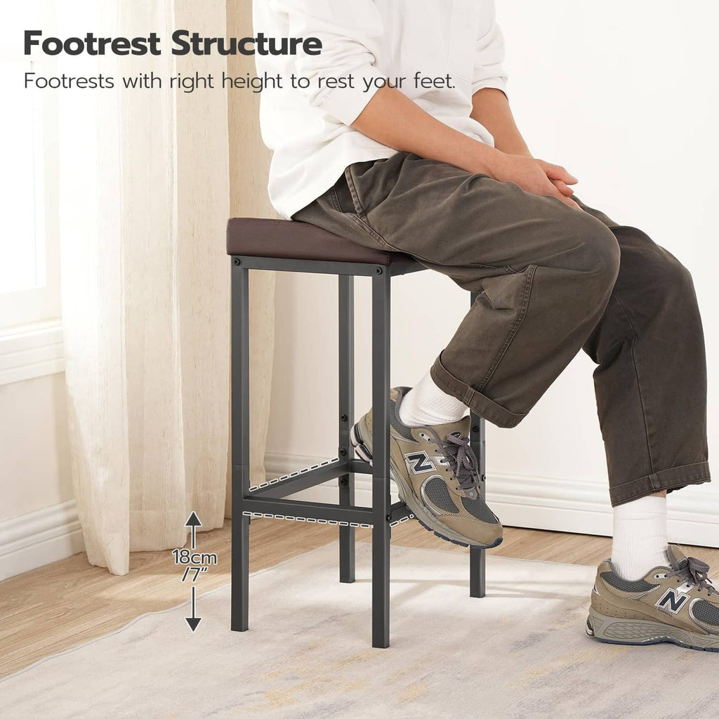 Bar stool with dark brown padded seat and black frame, person seated.