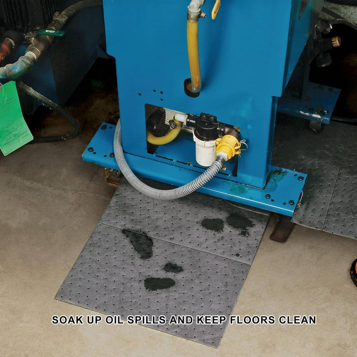 Gray oil absorbent pads laid flat under equipment with visible oil-soaked spots