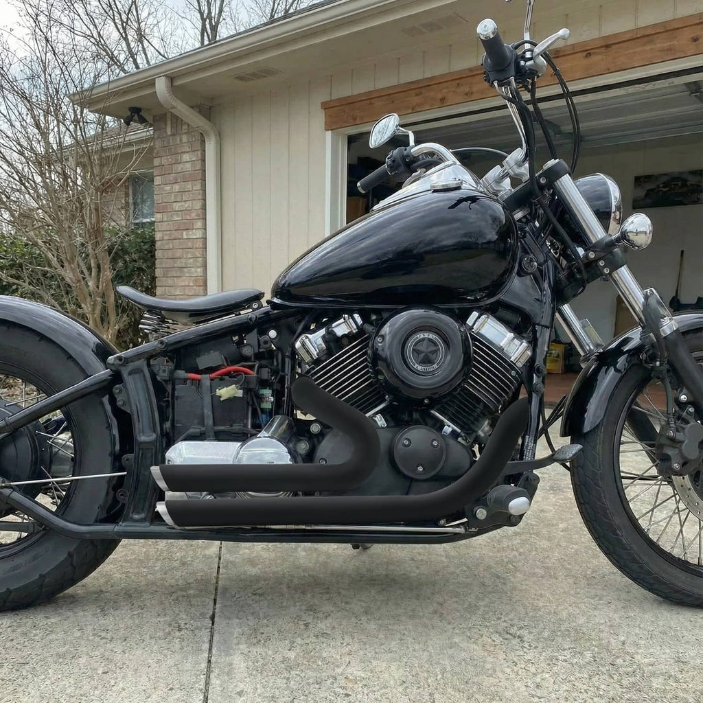 Black aftermarket exhaust pipes with chrome tips installed on a cruiser motorcycle.