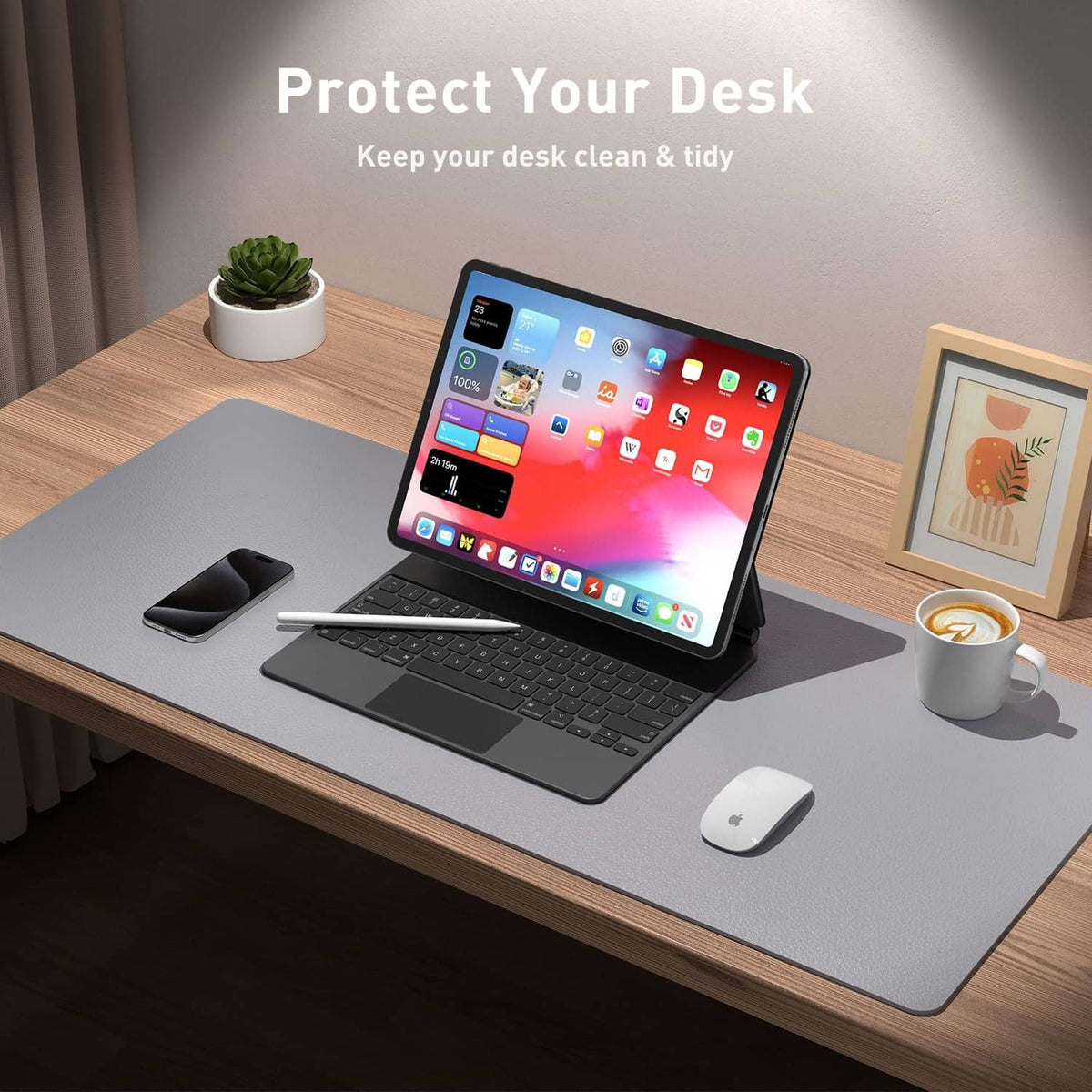 Light grey desk pad protector on office table under tablet, keyboard, and mouse
