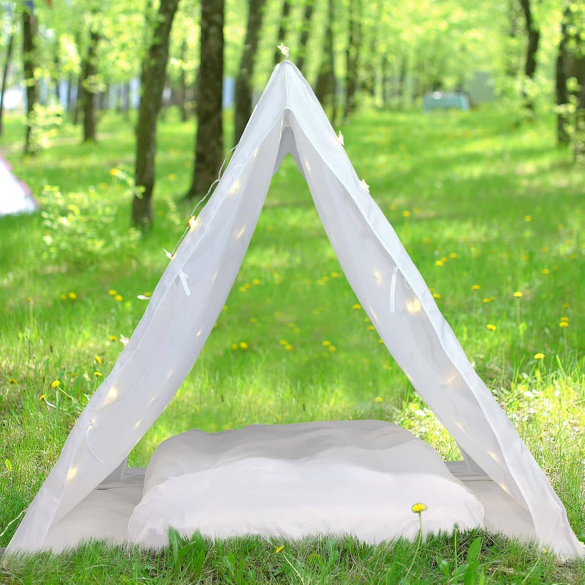 White outdoor teepee sleep tent with warm fairy lights and inflatable airbed