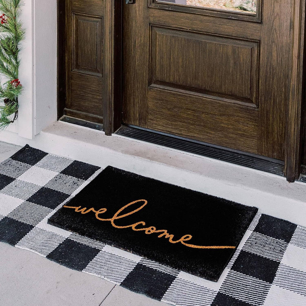 Outdoor black-and-white check coir doormat with orange “welcome”