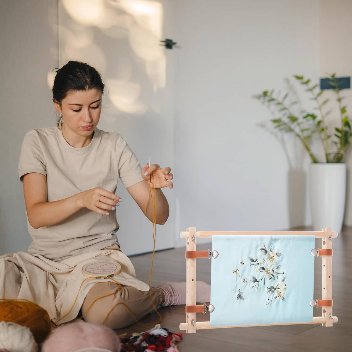 Wood needlepoint scroll frame in use with light-blue floral embroidery fabric