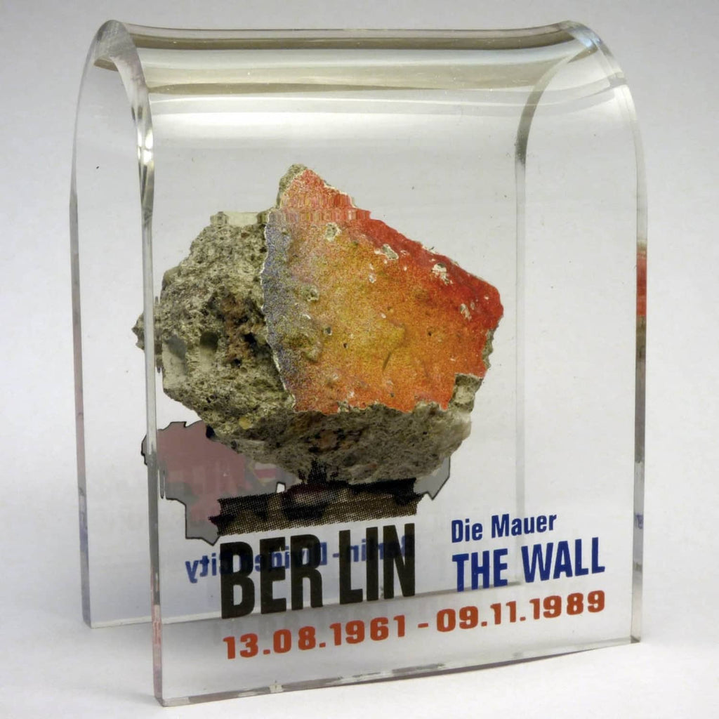 Acrylic display case showing rough rock specimen over Berlin Wall text, front view