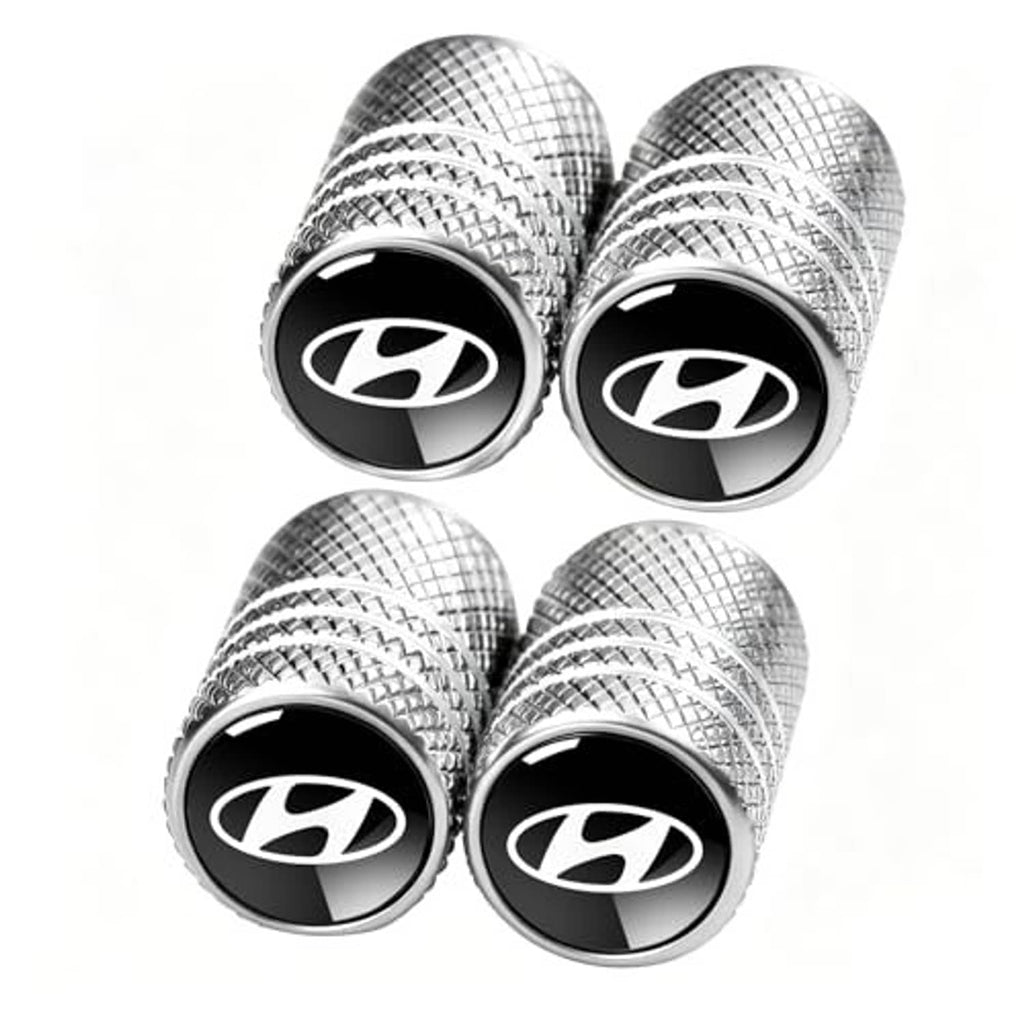 Four-pack silver plaid tire valve stem caps with black center logo emblem and ridged edge.