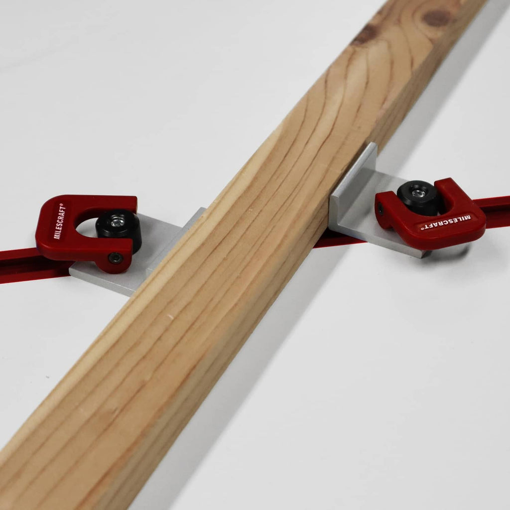 Red quick-adjust cam stop clamps on a T-slot rail against a light wood board