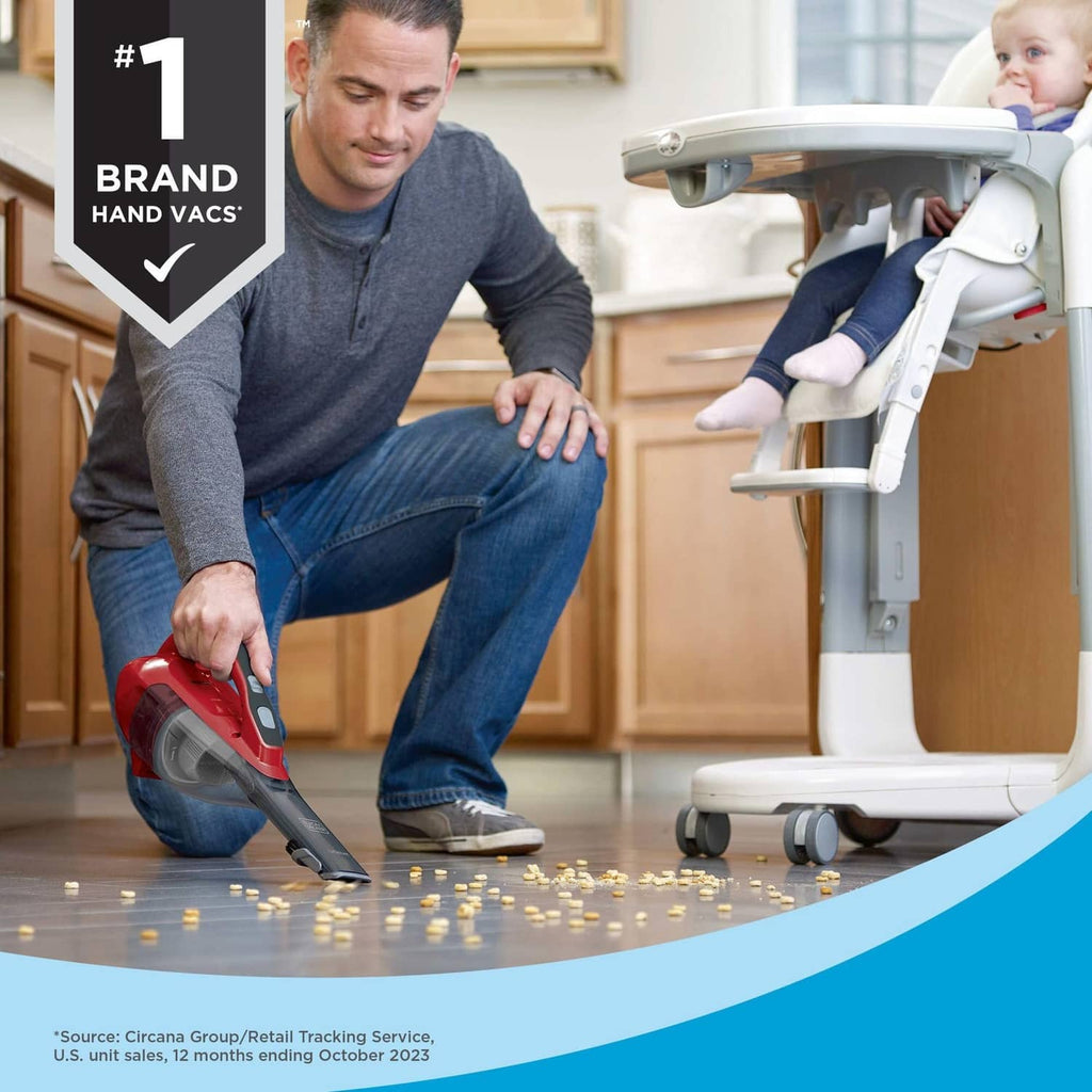 Cordless handheld vacuum in red and black being used on a floor near kitchen cabinets