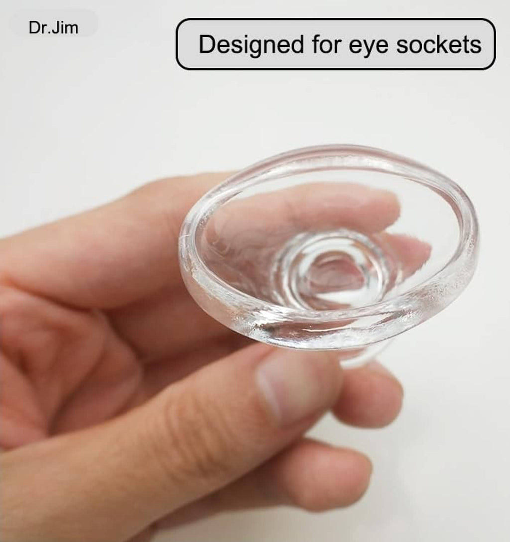 Clear glass eye rinse cup held in hand, concave rim