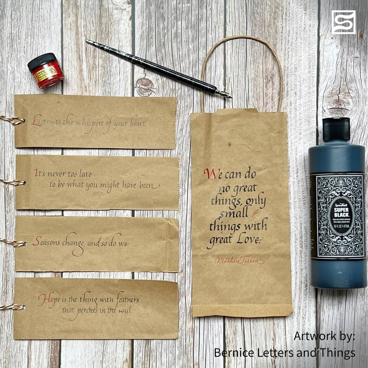 Black India ink bottle beside kraft paper cards for lettering