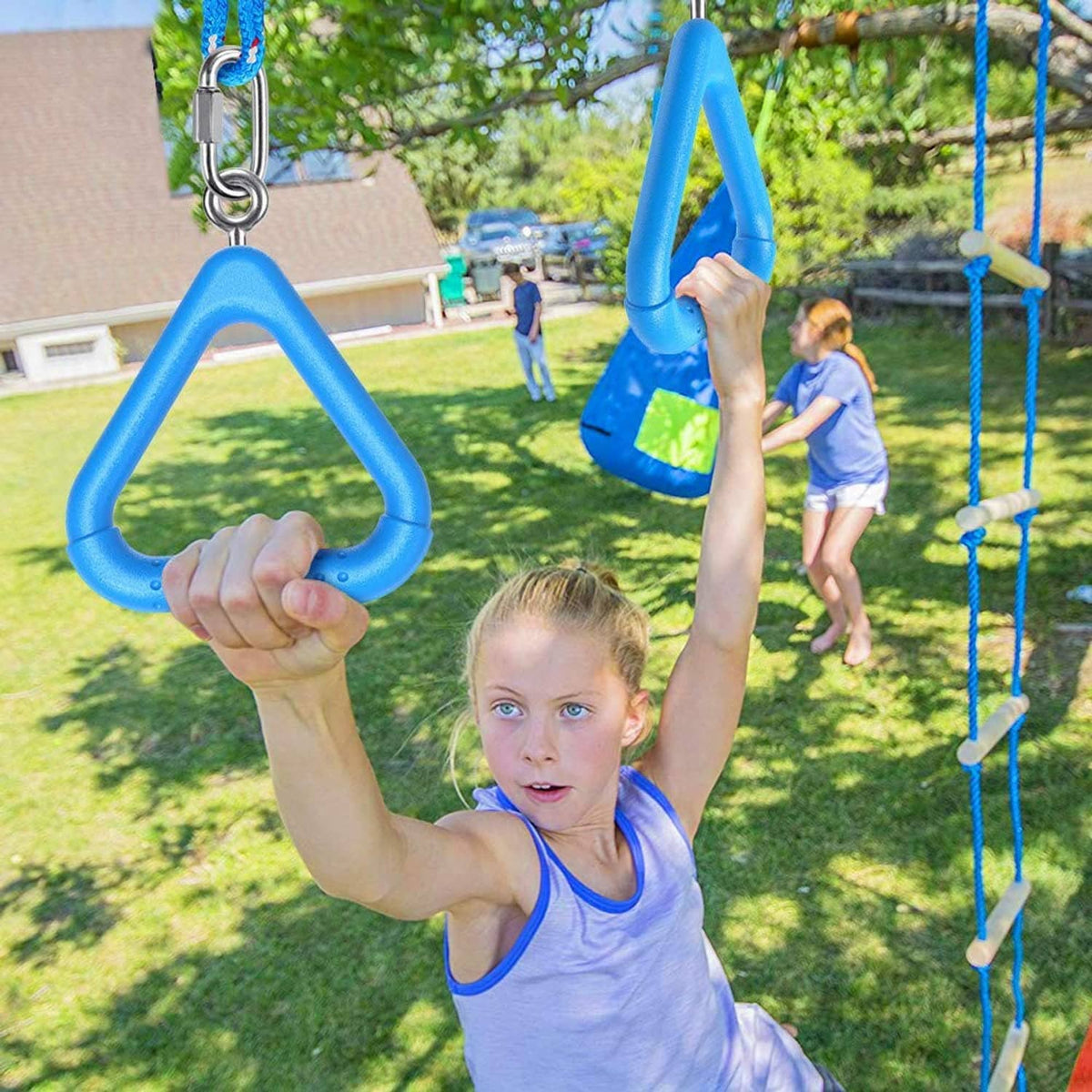 Blue trapeze swing bar rings with metal hooks held by a child's hands outdoors