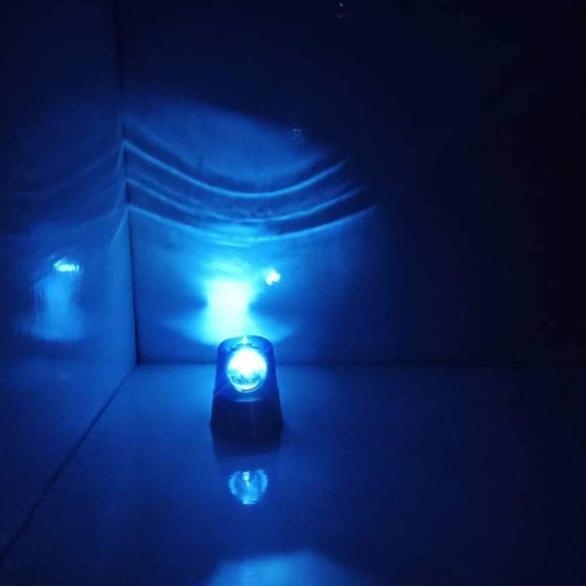Blue LED strobe disco light casting beams in a corner, small globe spotlight