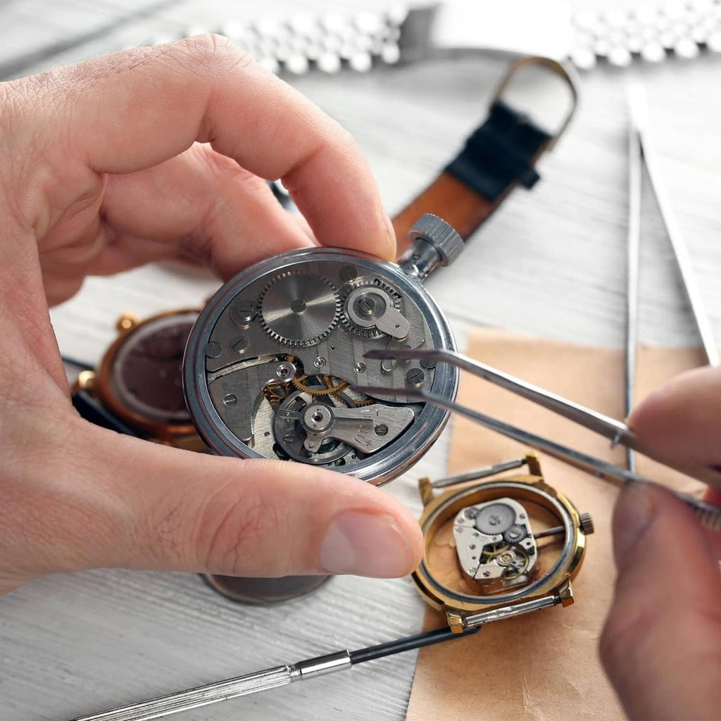 Watch battery clamp screw kit in use: silver screws and watch movement with tools