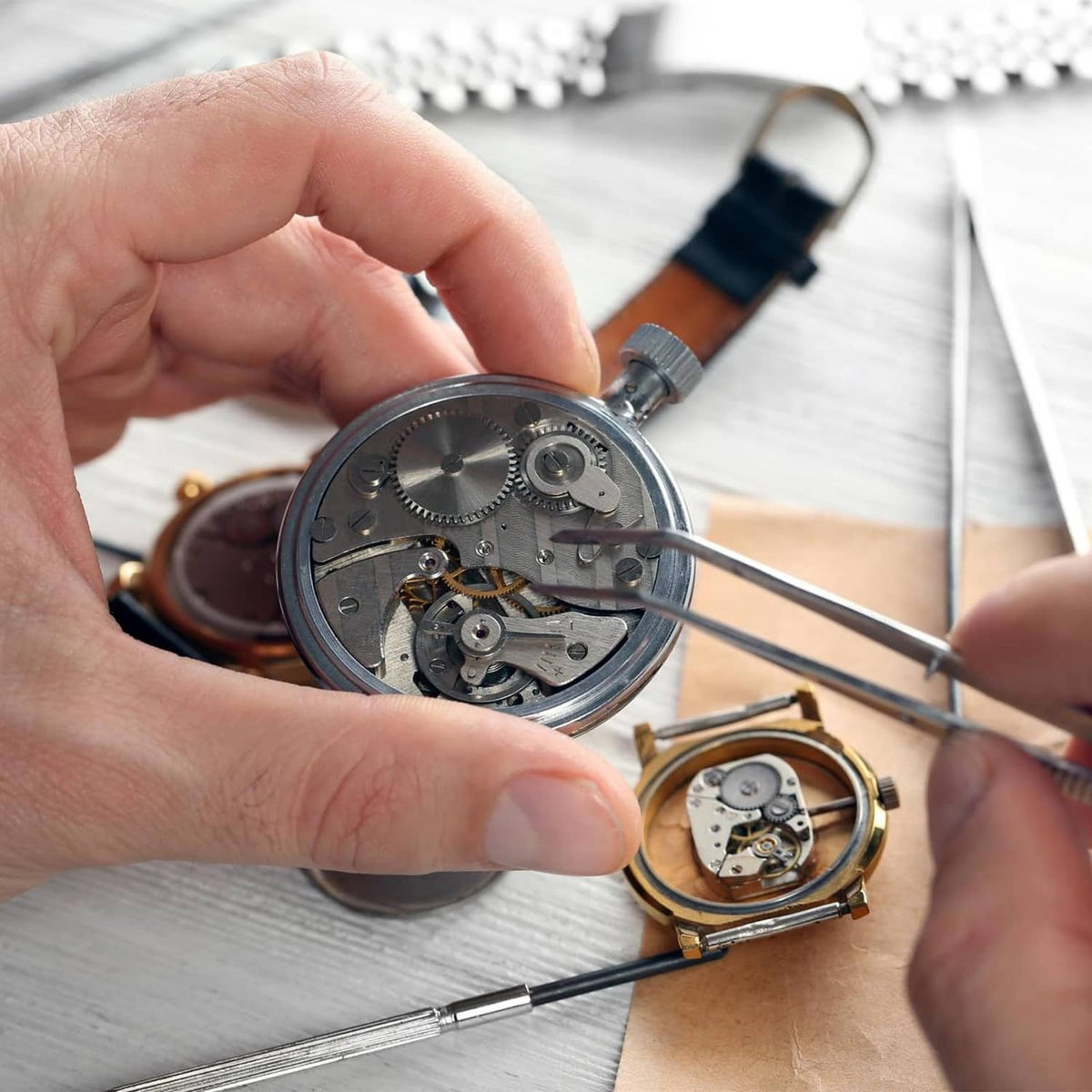 Watch battery clamp screw kit in use: silver screws and watch movement with tools