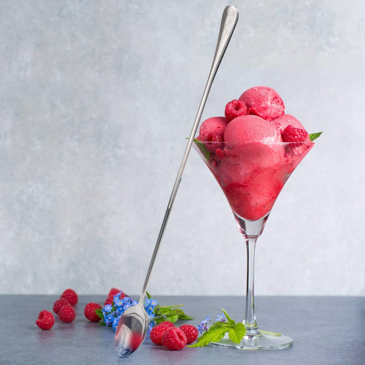 Stainless long handle mixing spoon standing in a raspberry dessert cup