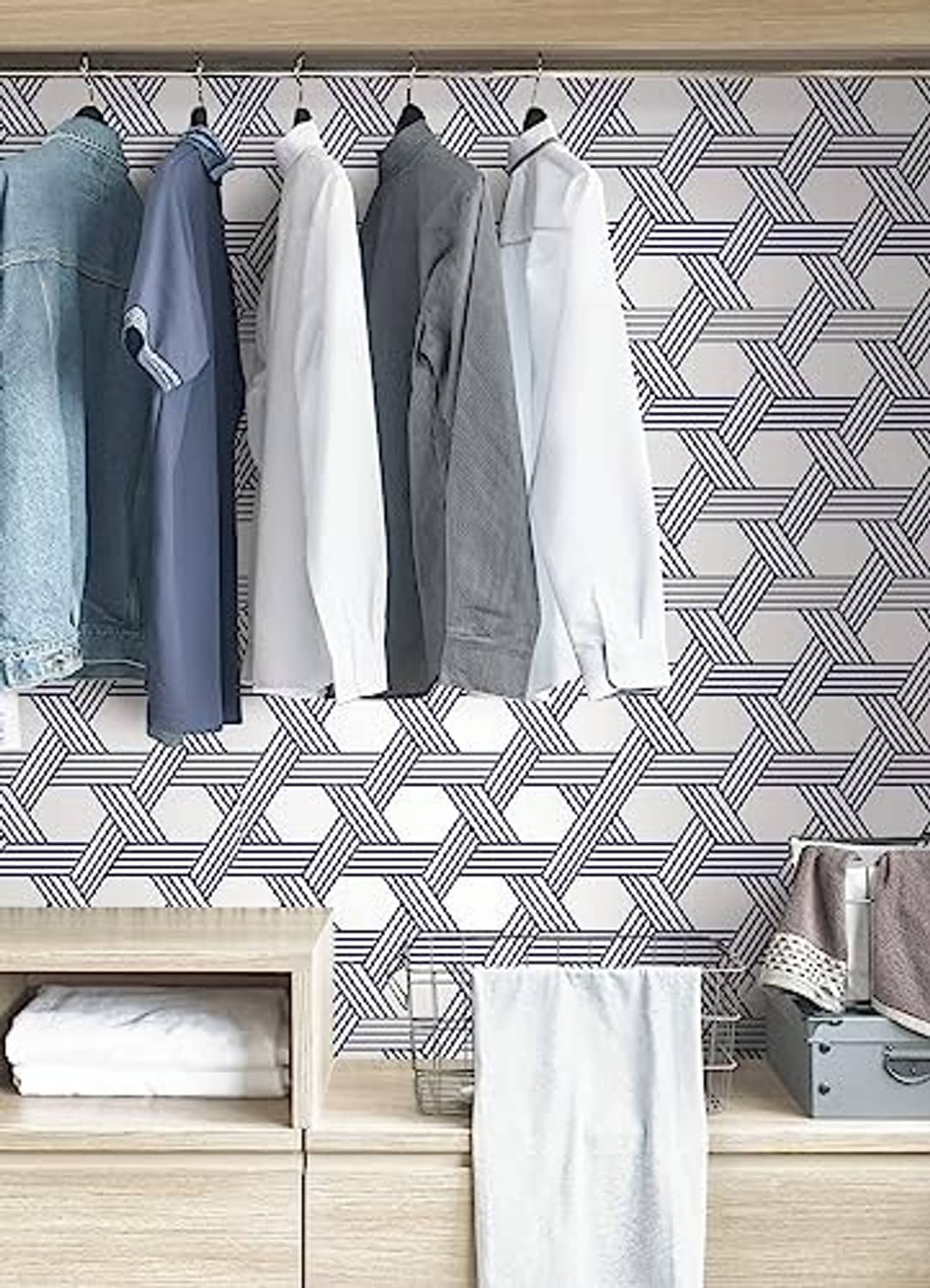 Blue-and-white geometric lattice wallpaper with hanging clothes nearby.