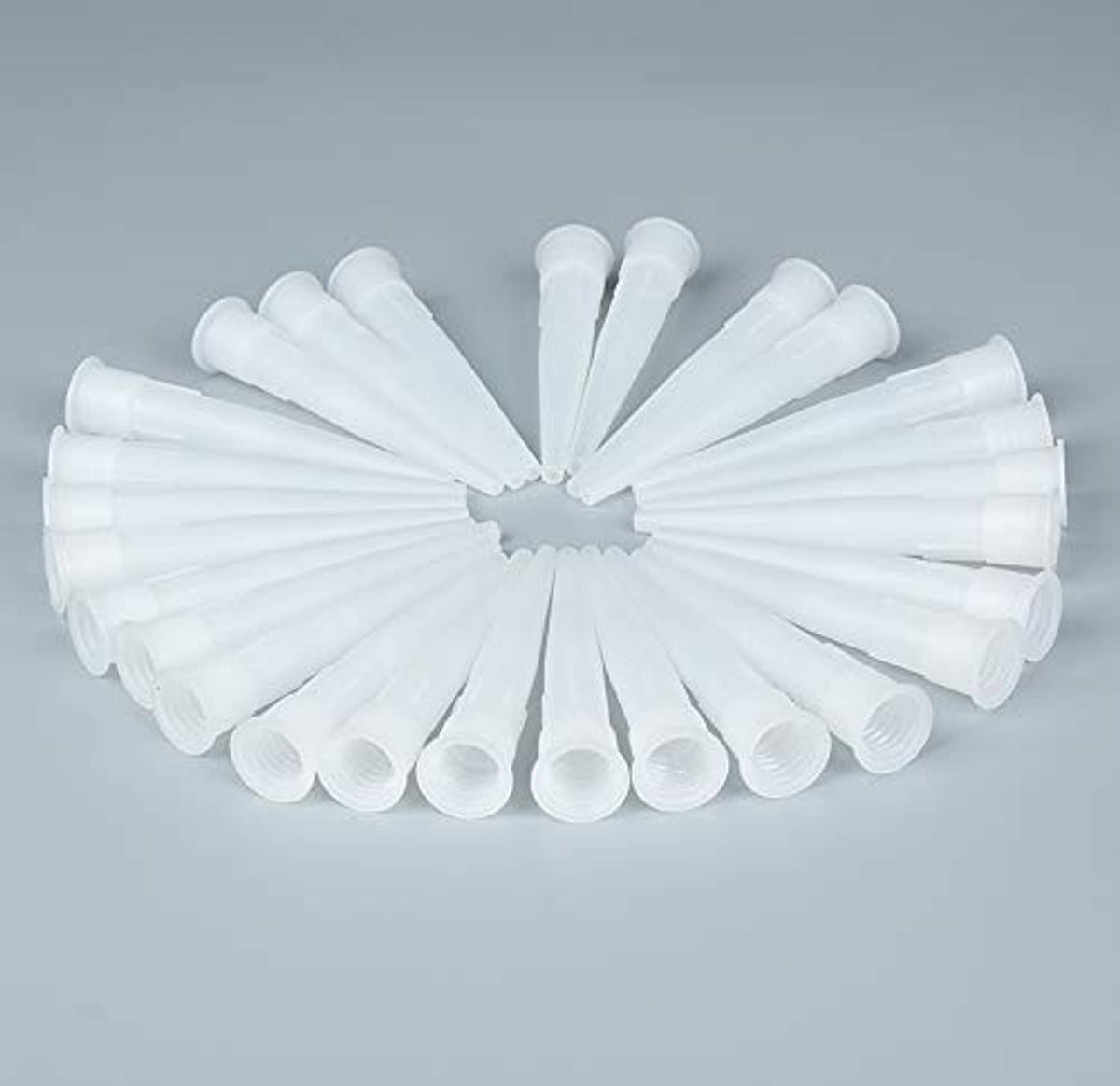 Assorted white plastic caulk nozzle tip extenders fanned out