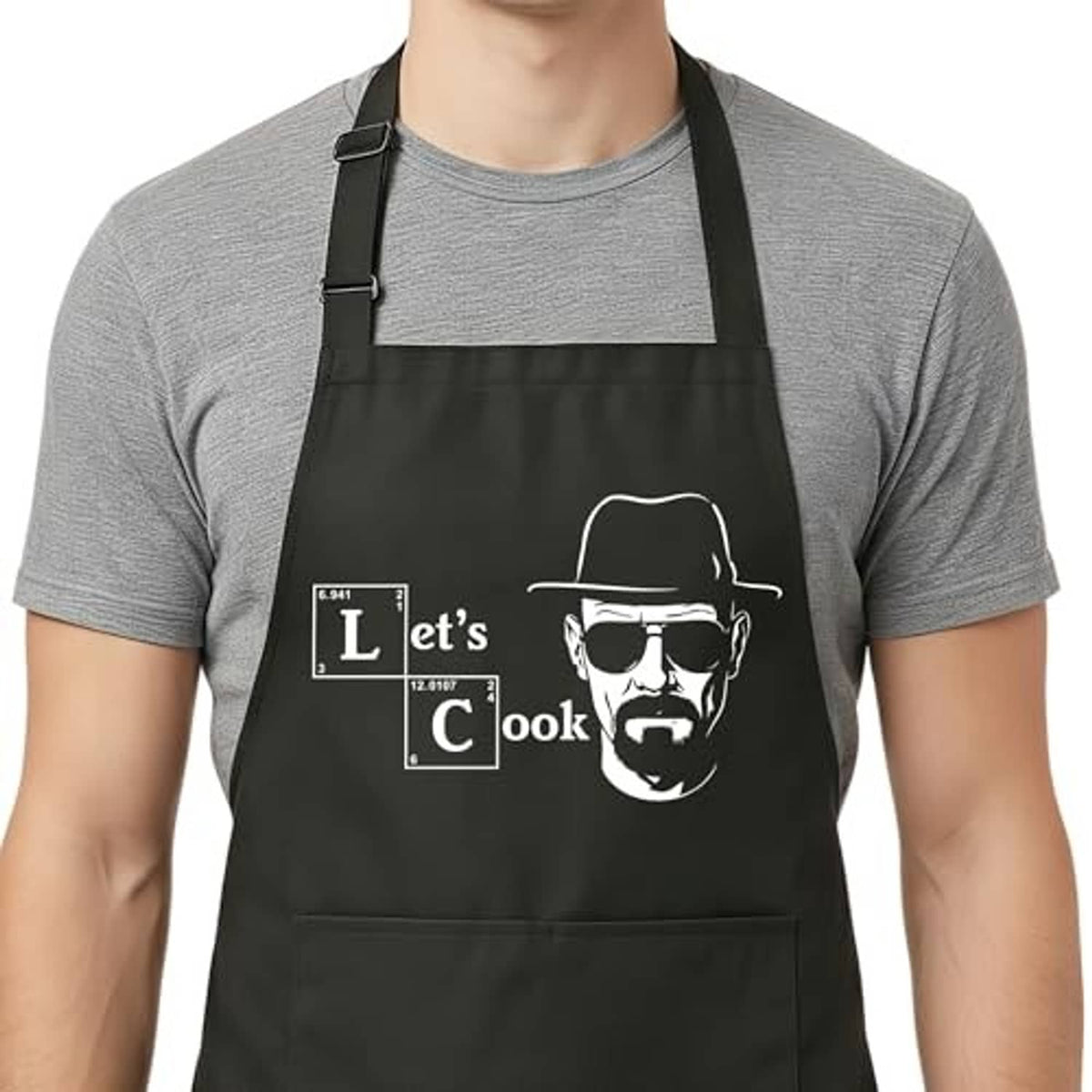 Black apron bib with “Let’s Cook” face graphic, front pocket, and adjustable neck straps
