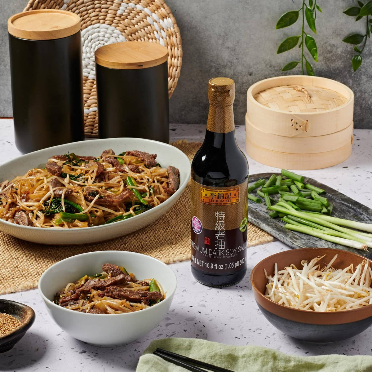 Lee Kum Kee premium dark soy sauce bottle among noodle and vegetable bowls